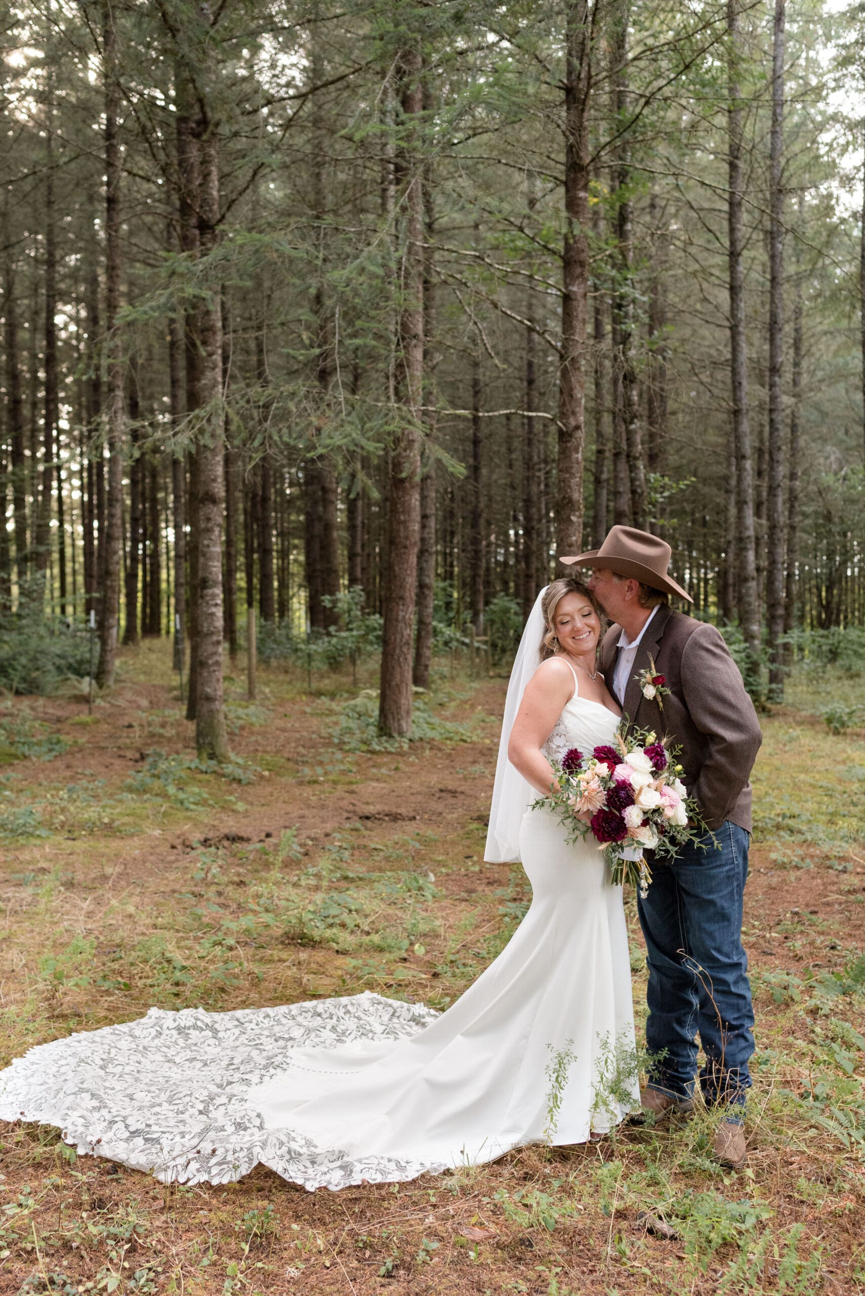 A groom kisses his bride on cheek in woodland setting in Lebanon, Oregon.