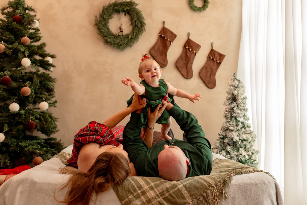 Mom, dad, and baby play airplane at a studio Christmas mini session in Lebanon, Oregon. 