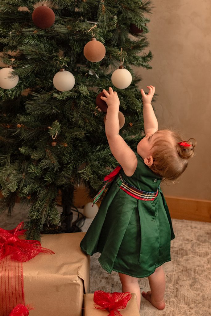 A baby reaches for ornaments on a Christmas tree at a studio in Lebanon, Oregon. 